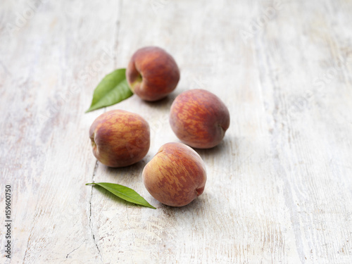 Four peaches on whitewashed wooden table