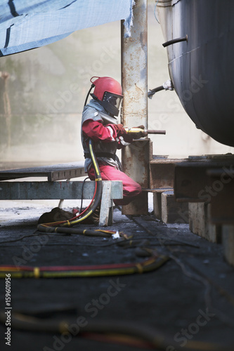 Worker sandblasting boat hull in shipyard photo