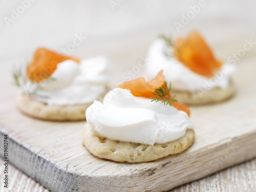 Soft cheese and smoked salmon garnished with dill on blini photo