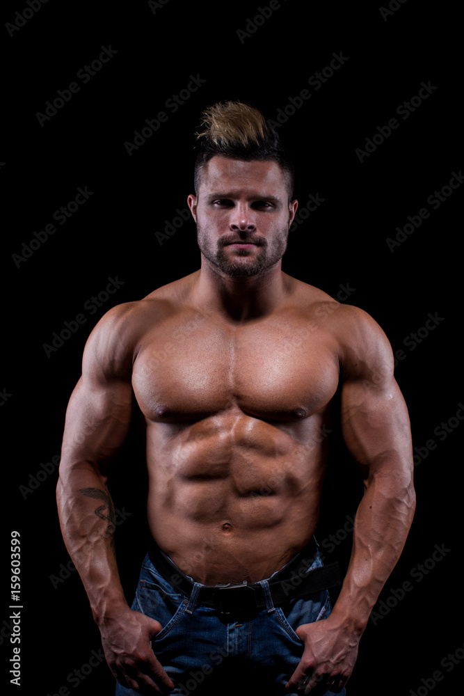 Studio shot of body parts of a topless muscular sportsman over black background