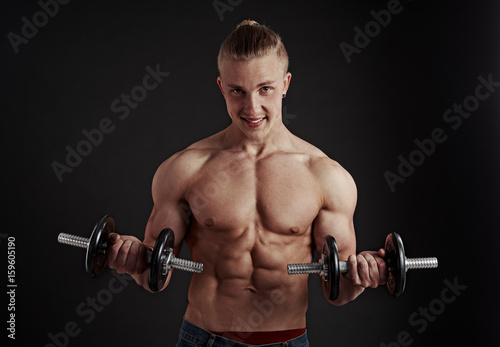 Handsome athletic man doing exercise with dumbbells, lifting weight. Concept of bodybuilding, sport and fitness. 