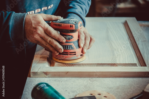 Photography Close-up of carpenter using sander for wood furniture