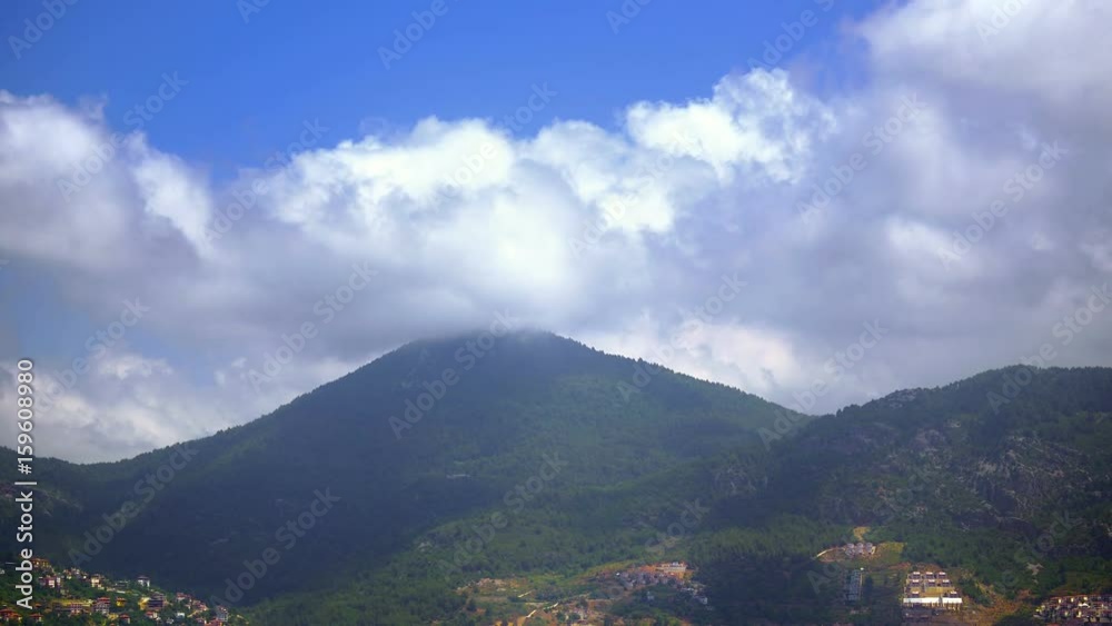 Rolling clouds over mountain ridges during sunrise with forest villages on the hillsides and layers of hills. Patches of sunlight and cloud shadows move on Taurus Mountains seen from Alanya in Turkey Rolling clouds over mountain ridges during sunrise with forest villages on the hillsides and layers of hills. Patches of sunlight and cloud shadows move on Taurus Mountains seen from Alanya in Turkey
