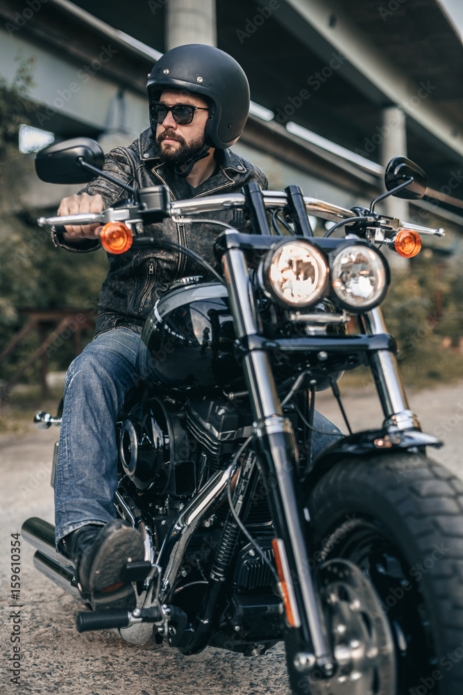 Biker in helmet and leather jacket sitting on a motorcycle. Freedom and travel concept. Biker in helmet and leather jacket sitting on a motorcycle. Freedom and travel concept.