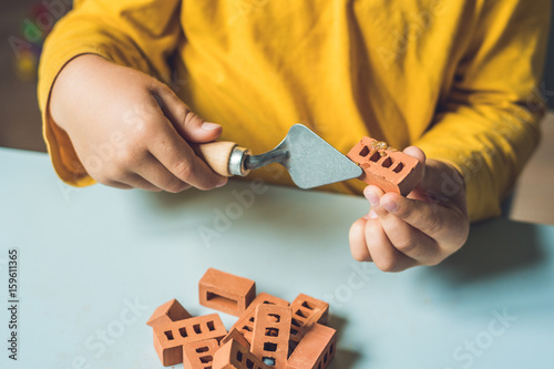 Close up of child's hands playing with real small clay bricks at the table. Toddler having fun and building out of real small clay bricks. Early learning. Developing toys. Construction concept photo