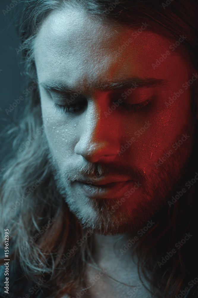 Close-up portrait of pensive bearded long haired man looking down