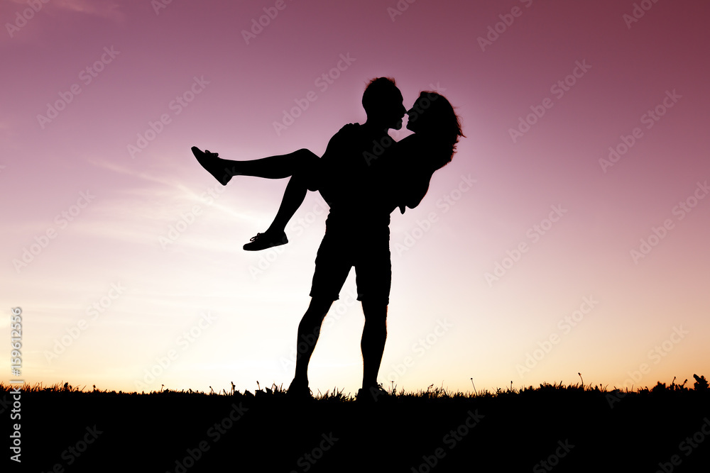 silhouette of romantic lovers with sunset on the back