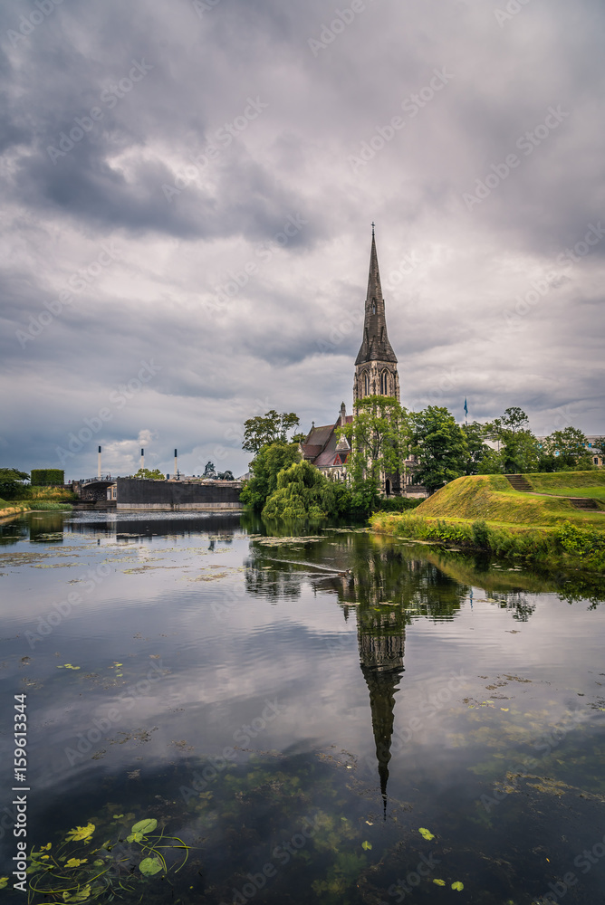 Church reflected on water pond in Churchill Park in Copenhagen a cloudy day of summer near sunset.