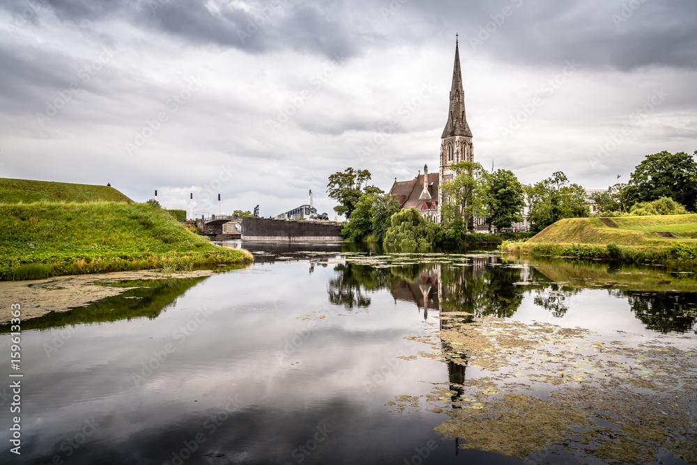 Church reflected on water pond in Churchill Park in Copenhagen a cloudy day of summer near sunset.