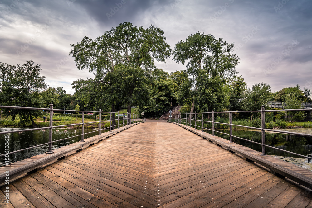Bridge over pond in Churchill Park in Copenhagen, Denmark, a cloudy day of summer