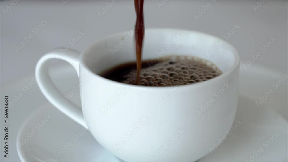 Fresh steaming aromatic coffee being poured into a white cup. Fresh steaming aromatic coffee being poured into a white cup.