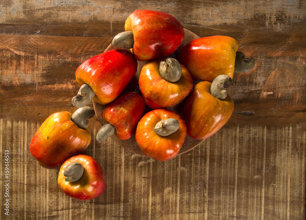 Some cashew fruit over a wooden surface.