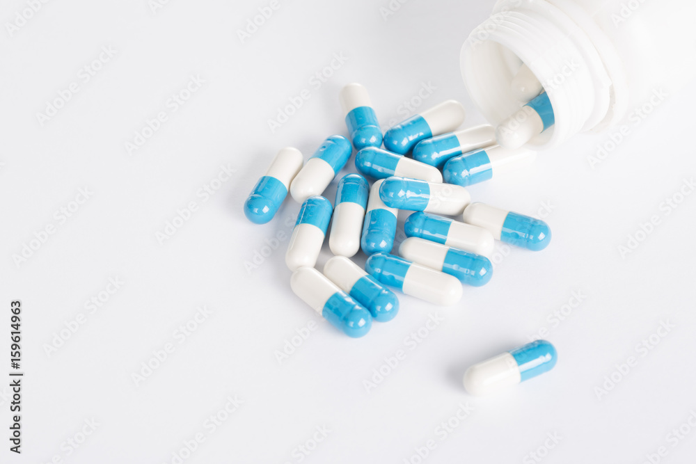 Blue pills in white pill bottle on white background. Blue pills in white pill bottle on white background.