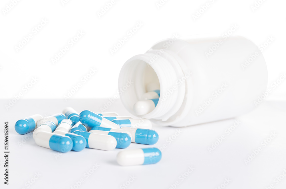 Blue pills in white pill bottle on white background. Blue pills in white pill bottle on white background.
