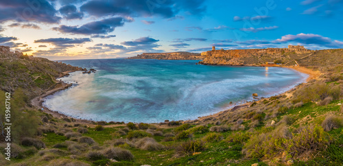 Mgarr, Malta - Panoramic skyline view of the famous Ghajn Tuffieha bay at blue hour on a long exposure shot with beautiful sky and clouds