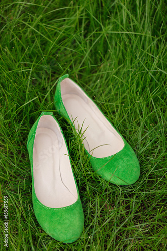 Green female shoes on grass. Blurred macro photo.
