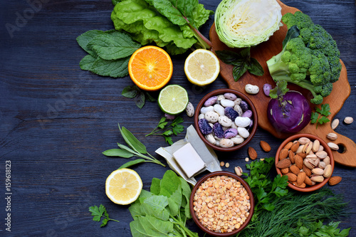 Composition on a dark background of products containing folic acid, vitamin B9 - green leafy vegetables, citrus, beans, peas, nuts, yeast. Top view. Flat lay