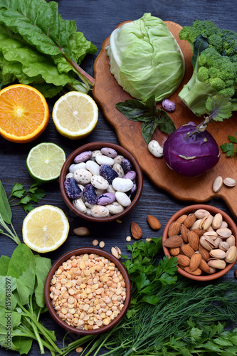 Composition on a dark background of products containing folic acid, vitamin B9 - green leafy vegetables, citrus, beans, peas, nuts, yeast. Top view. Flat lay