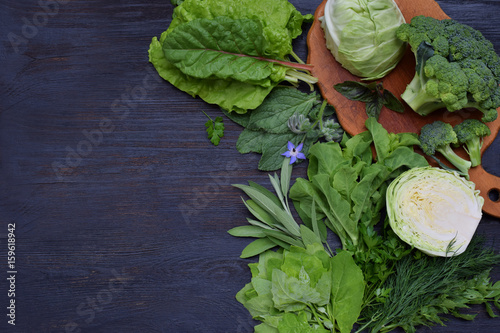 фотографія Composition on a dark background of green leafy vegetables containing folic acid, riboflavin, vitamin B9, B2, K, C - cabbage, broccoli, chard, lettuce, spinach, parsley, celery, dill, sage