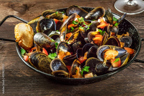 Skillet of marinara mussels on rustic background with copyspace