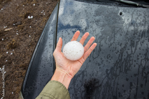 Storm chaser holds a baseball sized hailstone dropped by a supercell thunderstorm. photo
