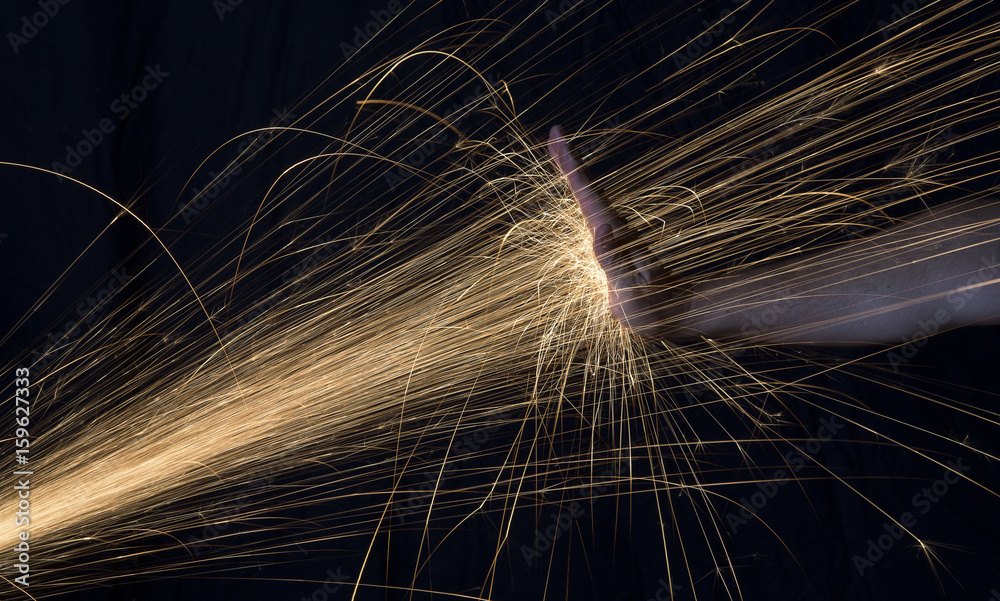 Long exposure photo of hand blocking glowing sparks from an angle grinder