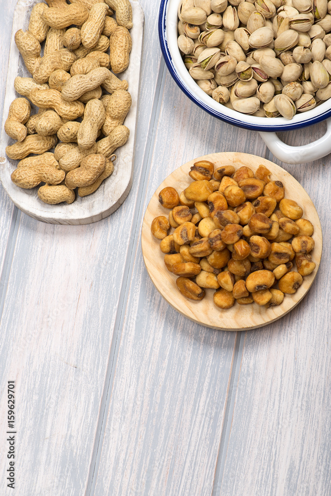 From above pistachios and toasted corn on wooden background. Vertical studio shot. From above pistachios and toasted corn on wooden background. Vertical studio shot.