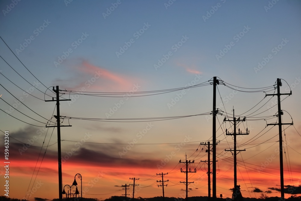 Telephone grid above and around railroad tracks provides a foreground to a colorful spring sunset in the Chicago suburban community of Bartlett, Illinois.