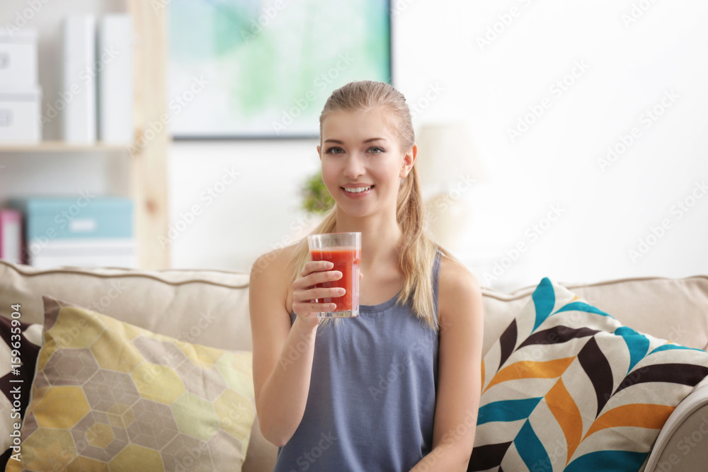 Φωτογραφία Young woman tasting fresh juice sitting on couch at living room