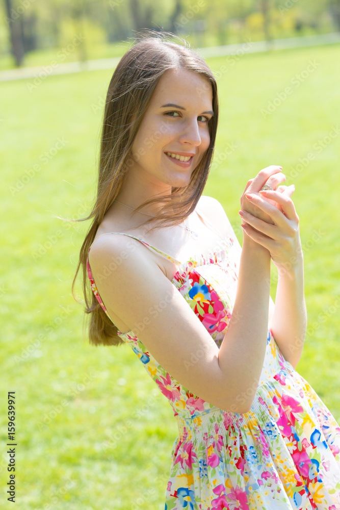Portrait of young beautiful woman with long hair wearing flower dress in green spring park Portrait of young beautiful woman with long hair wearing flower dress in green spring park