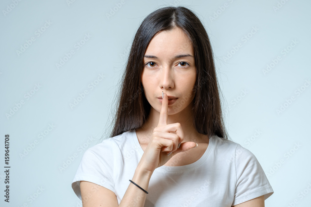 Keep silence! Beautiful young woman holding finger on lips Keep silence! Beautiful young woman holding finger on lips