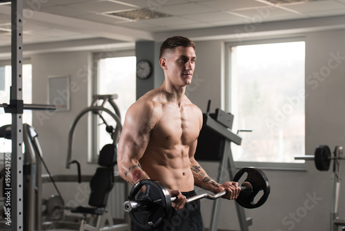 Man In The Gym Exercising Biceps With Barbell