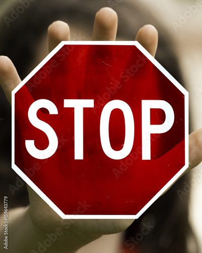 Young Girl Making a Stop Motion with a See-through Red Stop Sign Over her Hand photo