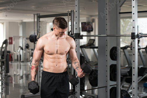 Young Man With Dumbbells Exercising Biceps