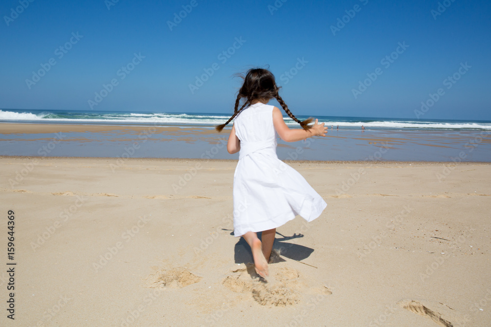 back view little girl running in sand beach with white dress