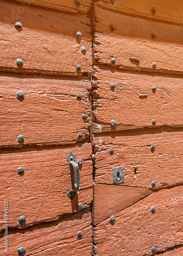 abstract wooden background wooden door with cracked paint on plaster with a metal handle and bolts.