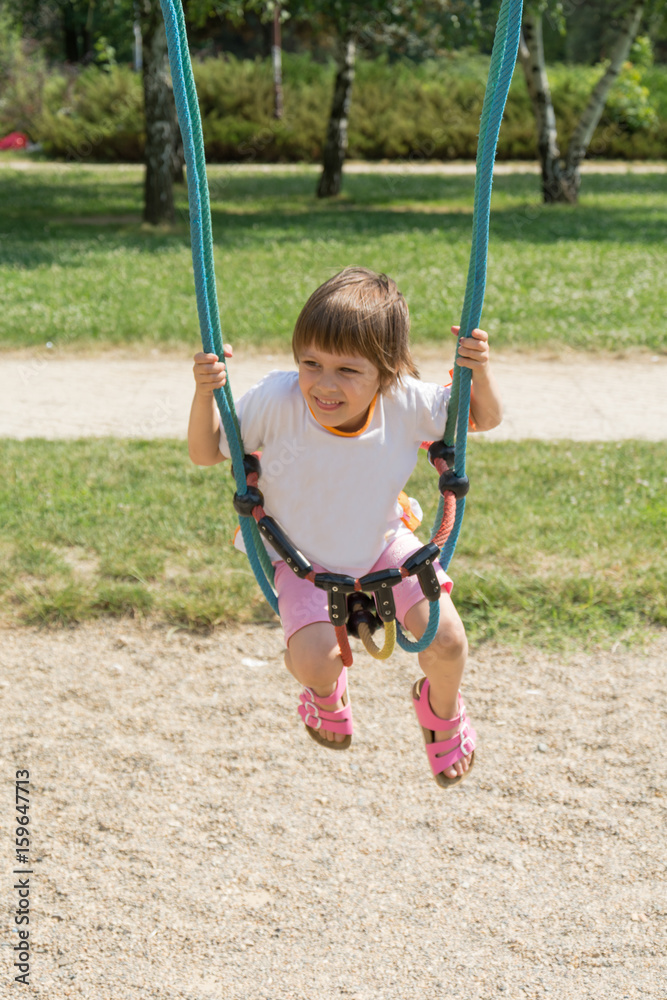 Happy little girl on swing at playground