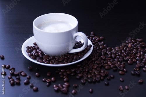 Hot coffee in the white cup and roasted on dark background 