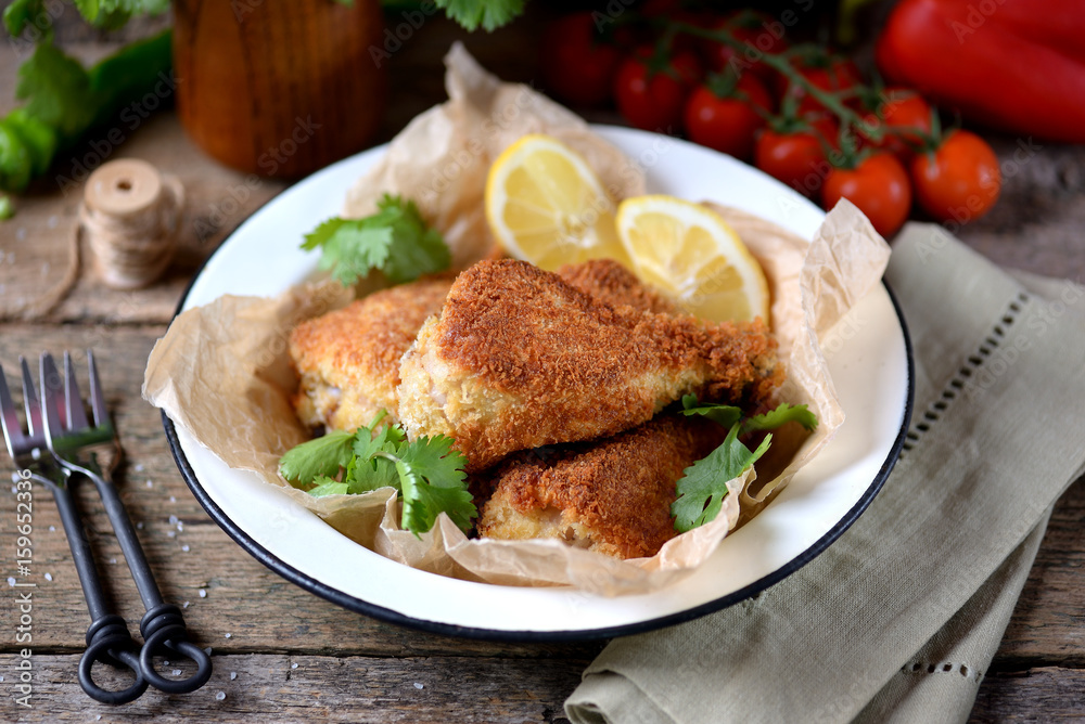 Chicken legs fried in breadcrumbs in deep-fried, rustic style. Old wooden background.