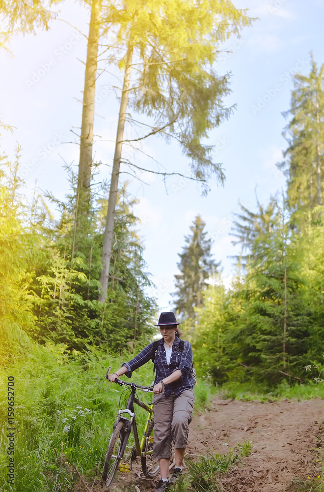 Obraz premium The girl is riding a bicsycle in the woods