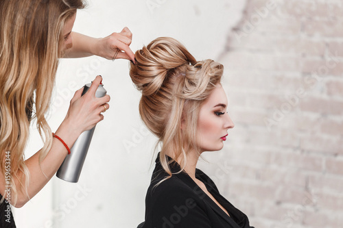 Professional Hairdresser using hair spray on client business woman hair at beauty salon