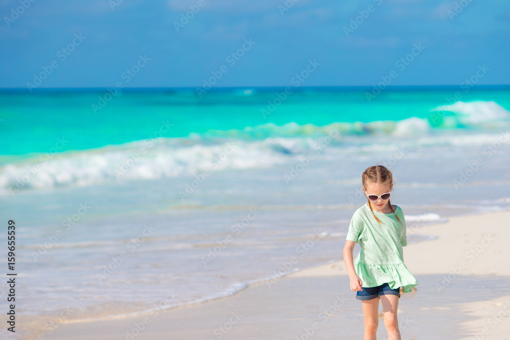 Happy little girl walking on the white beach
