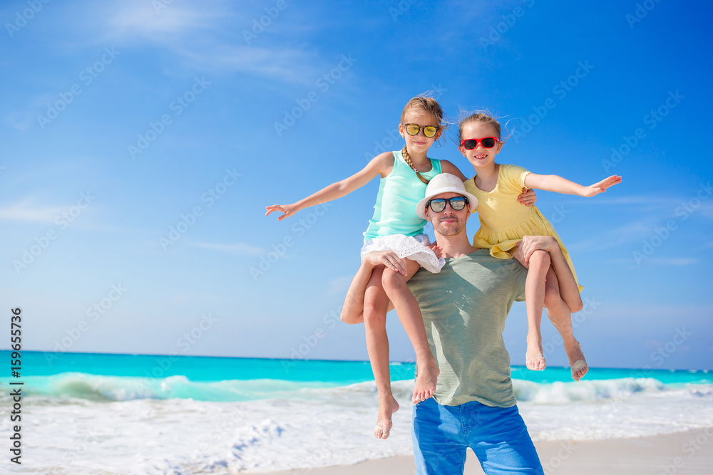 Family of dad and kids walking on white tropical beach on caribbean island have a lot of fun