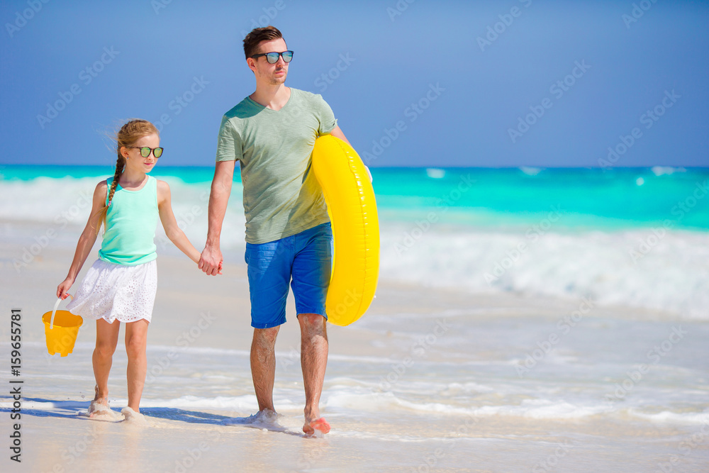 Little girl with beach toys walking along the sea with father. Family vacation. Little girl with beach toys walking along the sea with father. Family vacation.
