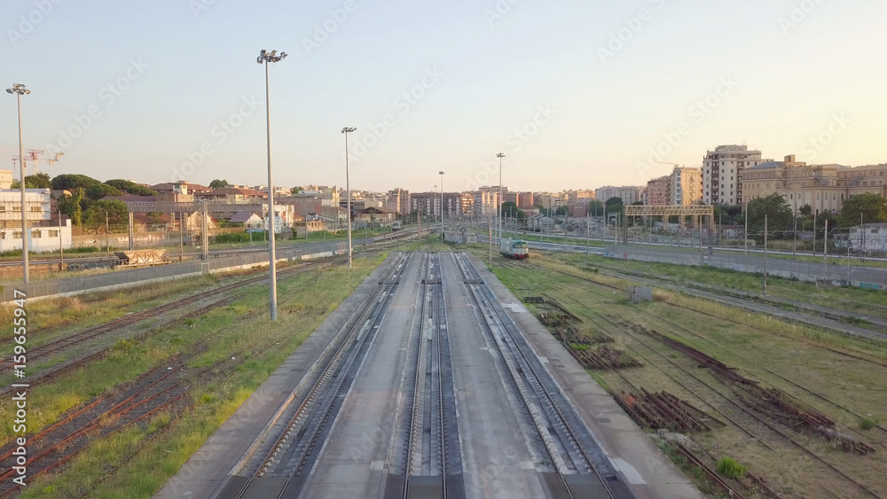 Vista aerea dei binari di una ferrovia e panorama della città di Roma vicino la Stazione Tuscolana, poco prima del tramonto