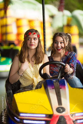 Happy girlfriends driving a bumper car together