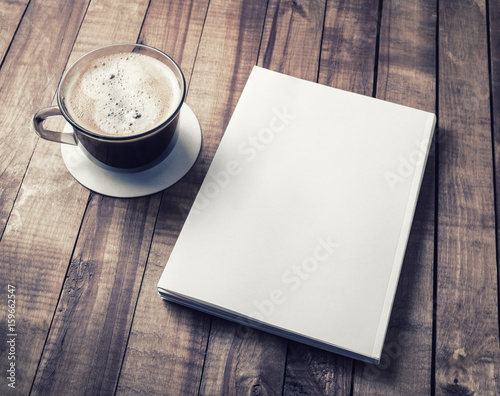 Blank closed book and coffee cup on vintage wooden background. Responsive design template.