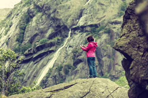 Woman on mountain rock enjoying beautiful view