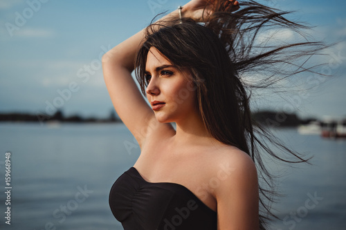 Girl by the water holding hair in the wind