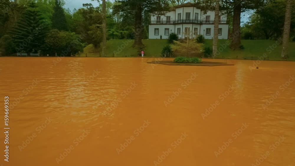 Tilting shot of yellow iron water heated thermal pool in the edenic Parque Terra Nostra, Furnas, Sao Miguel, The Azores, Portugal. Tilting shot of yellow iron water heated thermal pool in the edenic Parque Terra Nostra, Furnas, Sao Miguel, The Azores, Portugal.